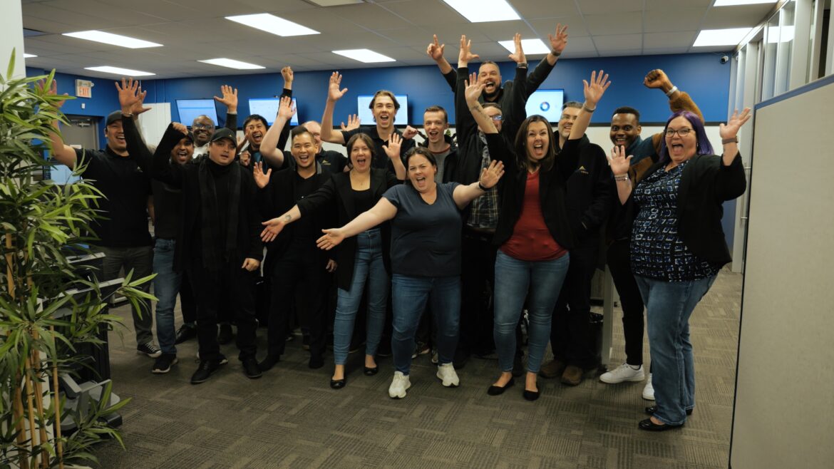 Diverse group of colleagues in office raising their hands in celebration