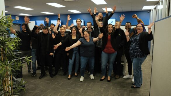 Diverse group of colleagues in office raising their hands in celebration