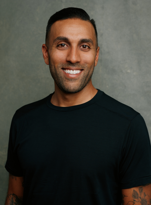 Man with short dark hair and beard smiling, wearing a black t shirt