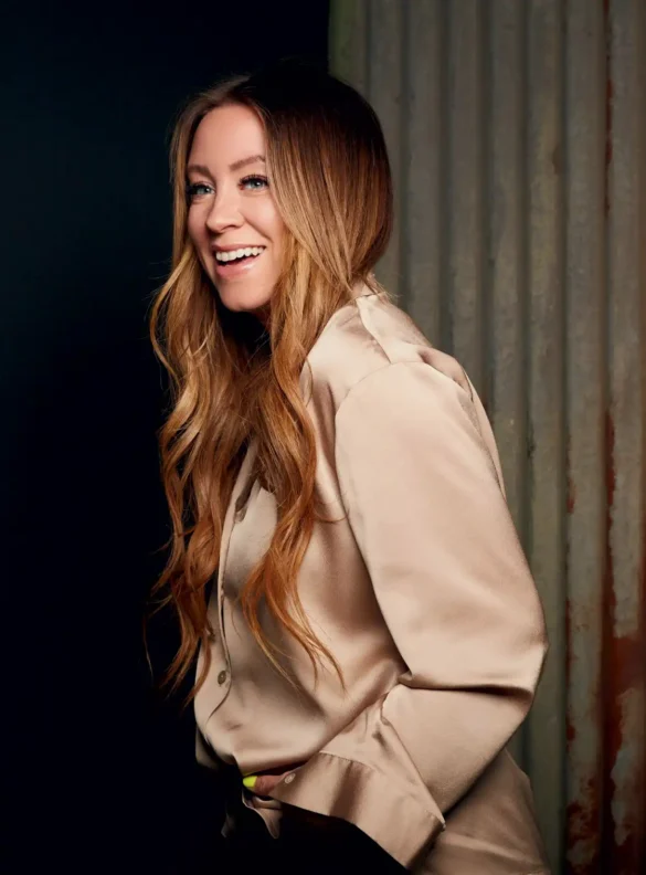 Smiling blonde woman in satin shirt with wavy hair