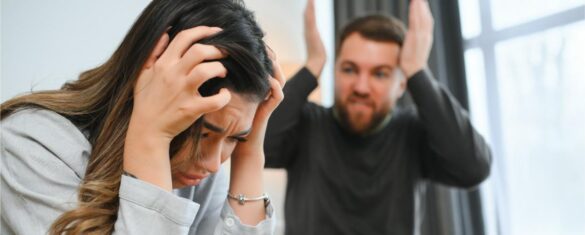 Woman distressed with hands on head, man shouting in background