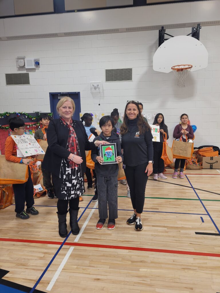 Children and adults receive gift bags and art at a school event.