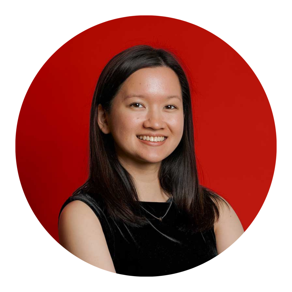 Young woman with dark hair smiles in a black sleeveless top against a red background.