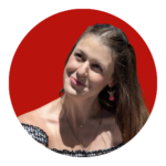A young woman with long brown hair and cherry earrings looks up coyly against a red background.