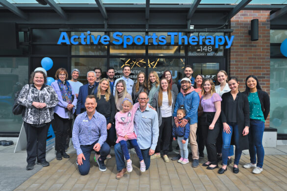 Active Sports Therapy team poses outdoors in front of their clinic signage.
