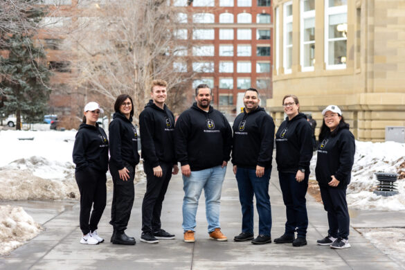 Team of 7 people in black Bloom Benefits hoodies and casual wear outdoors in winter.