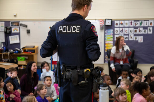 Police officer presents to engaged elementary school children in a classroom.
