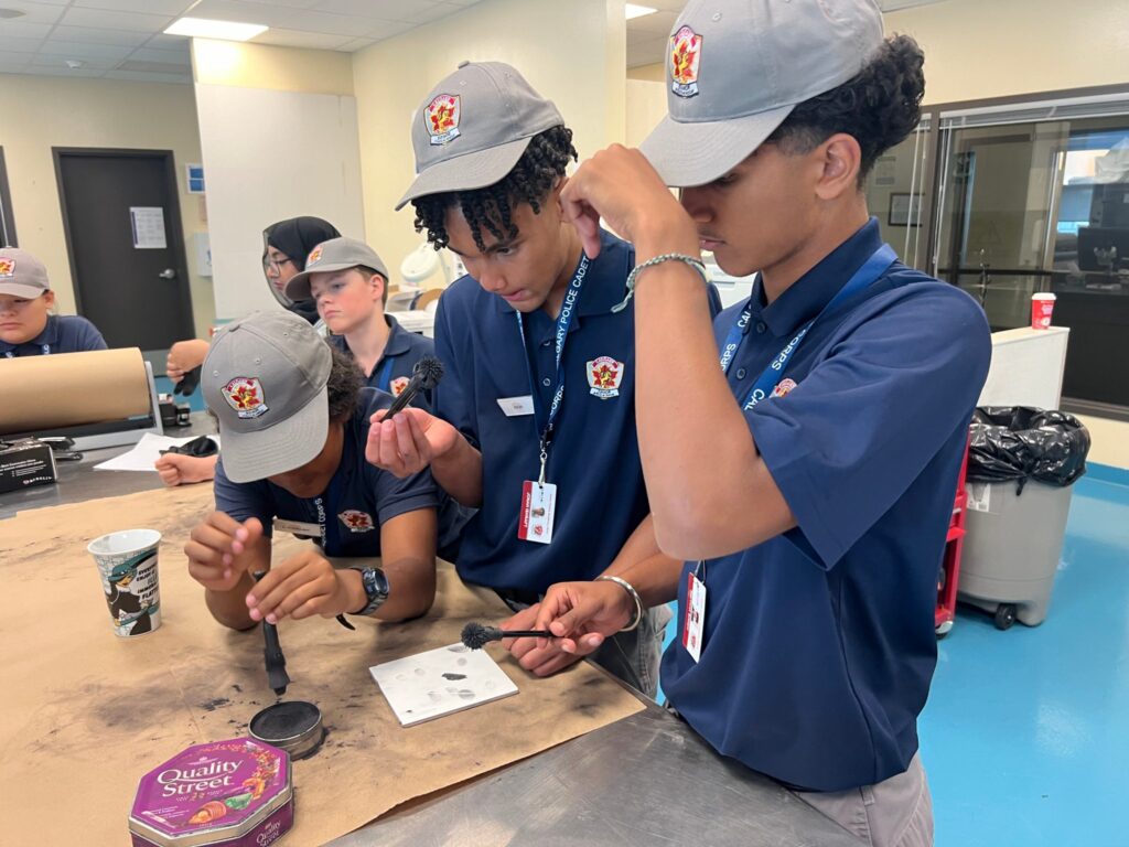 Police cadets learn fingerprinting techniques with ink and brushes.