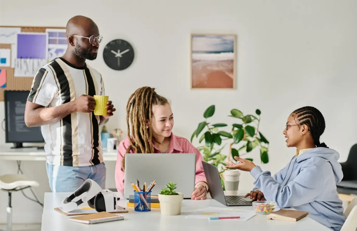 Diverse team collaborating at desks with laptops in modern office