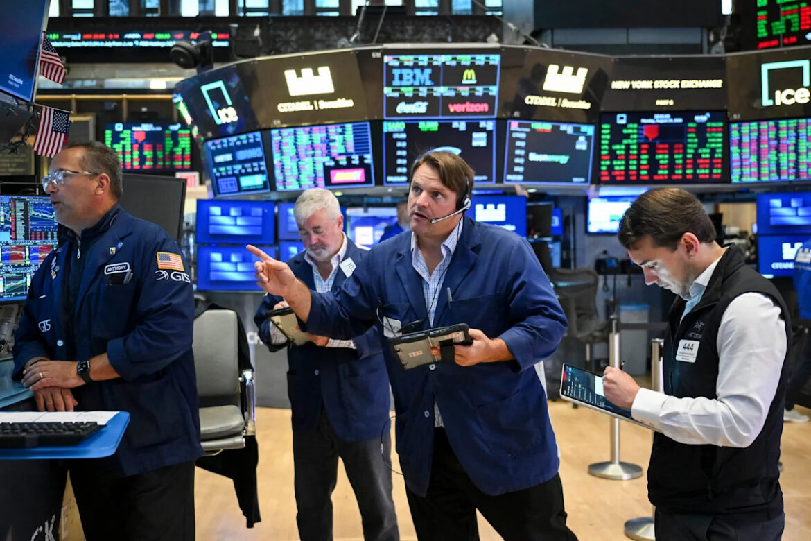 Stock market trading floor with declining indices displayed on screens