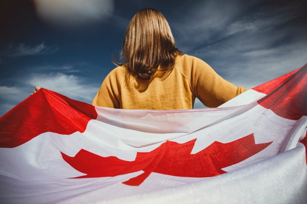 A woman holding the Canadian flag with mountains in Banff, Alberta, Canada.