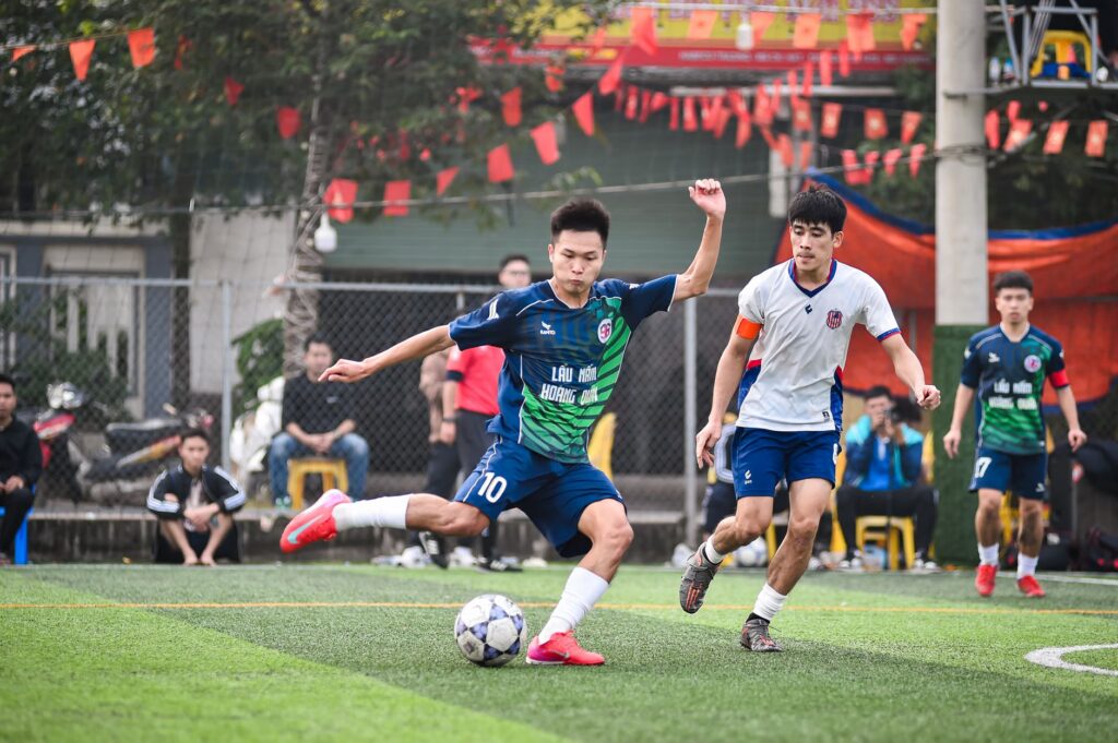 Action-packed soccer game with players competing fiercely on a turf field in Hanoi.
