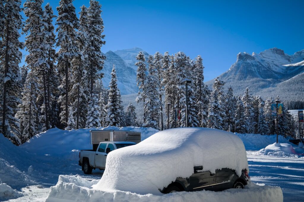 Snow-covered car and evergreen trees in a Canadian winter landscape.