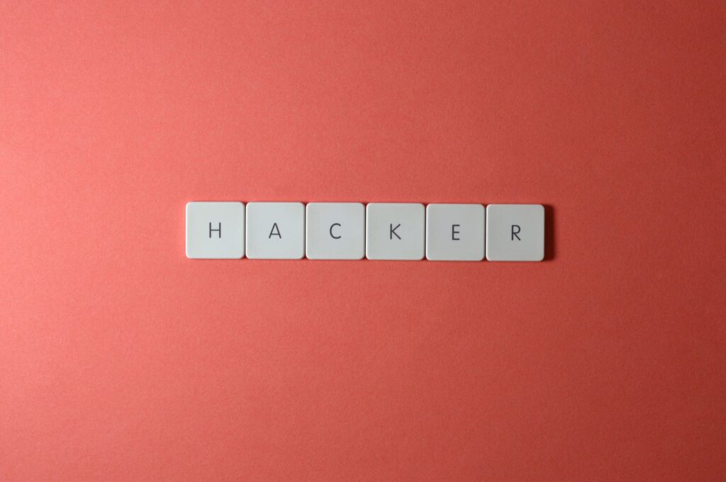 Close-up of the word 'HACKER' made with letter tiles on a red background, emphasizing cybersecurity.